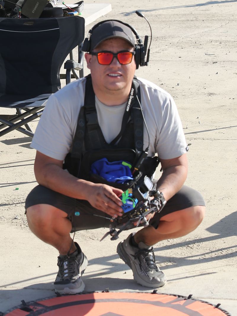 David Escobar crouched at the launch pad in the pits, FPV quad in hand.