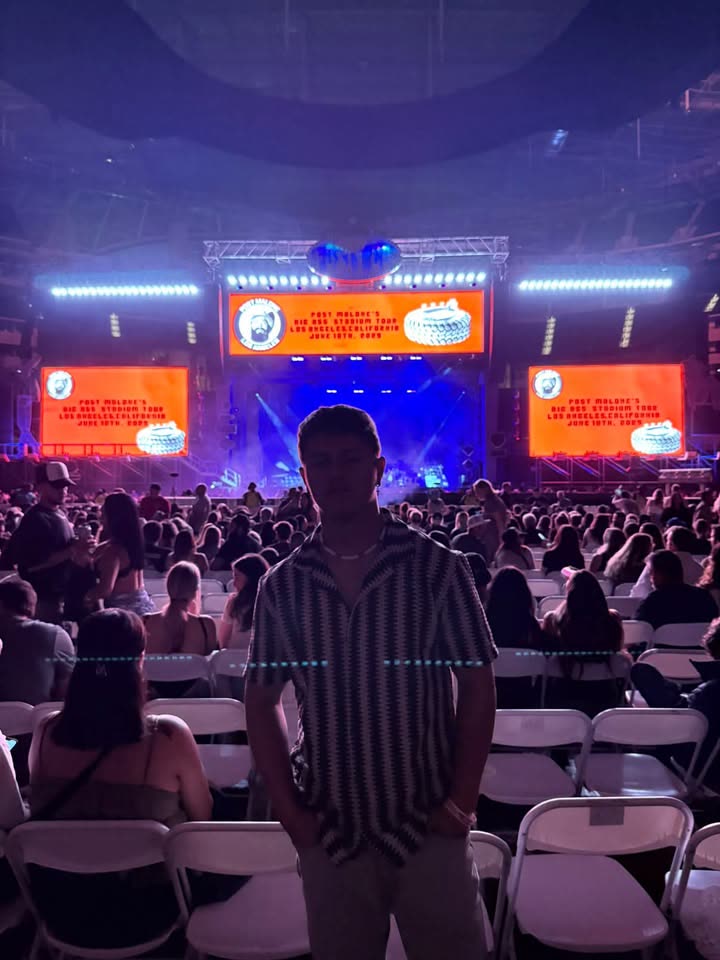 Dylan Davis standing in a stadium crowd, stage screens lit up behind him.